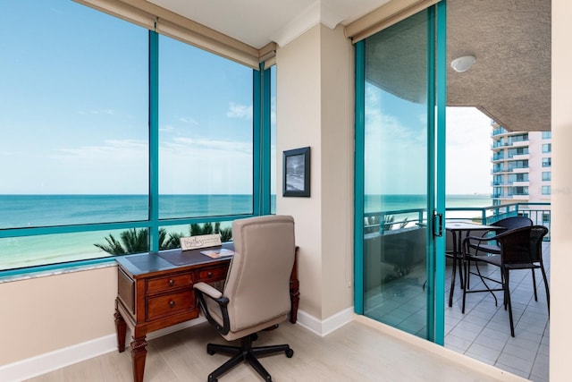 home office featuring a wall of windows, a water view, wood finished floors, and baseboards