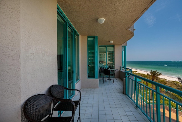 balcony featuring a water view, a sunroom, and a beach view