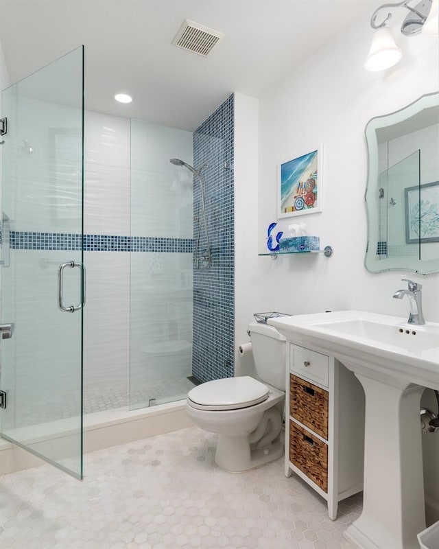 bathroom featuring toilet, a shower stall, and visible vents