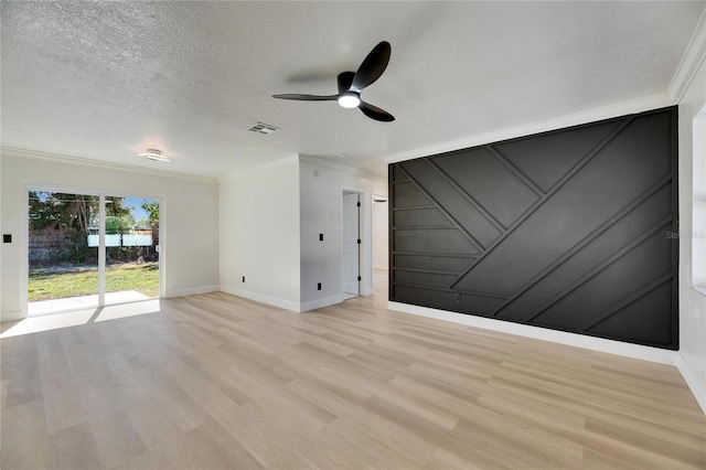 spare room with a textured ceiling, visible vents, baseboards, ornamental molding, and light wood-type flooring