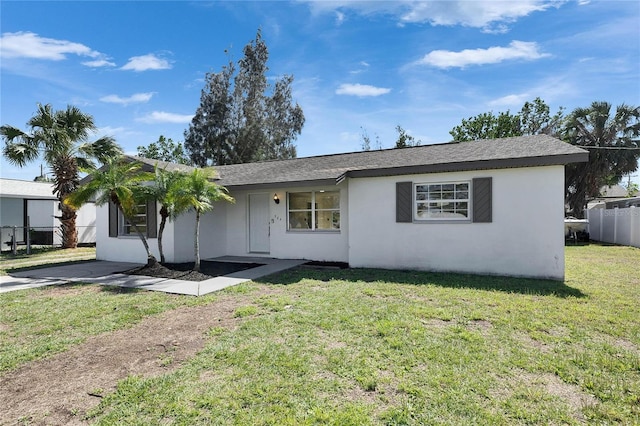 ranch-style home with roof with shingles, a front yard, fence, and stucco siding