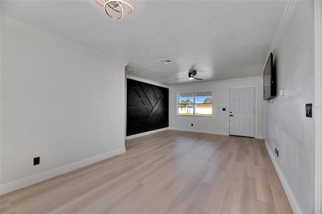 interior space featuring ceiling fan, a textured ceiling, baseboards, ornamental molding, and light wood finished floors