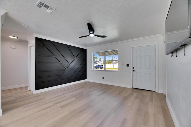 empty room featuring ceiling fan, light wood-style flooring, a textured ceiling, and visible vents