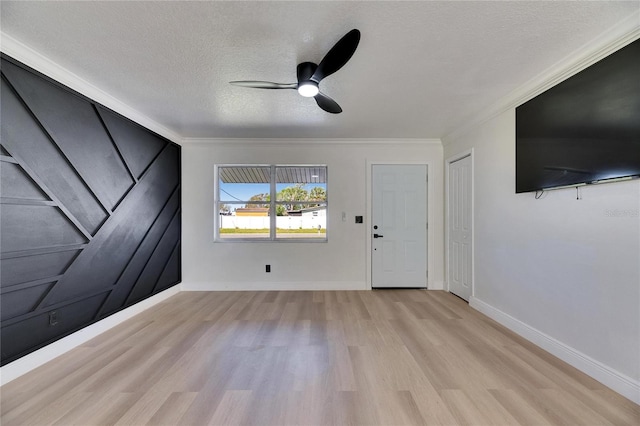 interior space with baseboards, a ceiling fan, light wood-style flooring, crown molding, and a textured ceiling