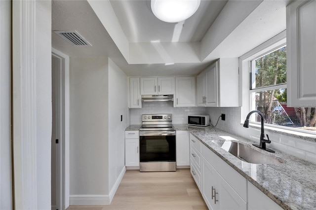 kitchen with under cabinet range hood, a sink, visible vents, stainless steel electric stove, and light wood finished floors