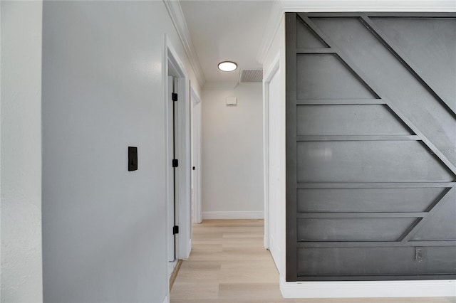 hallway featuring light wood-style floors, visible vents, and baseboards