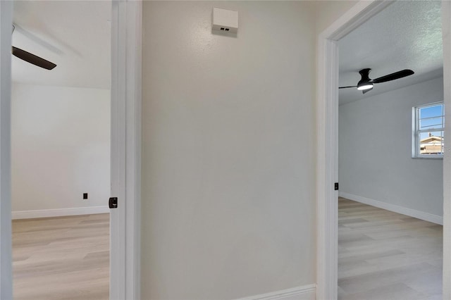 corridor with baseboards and wood finished floors