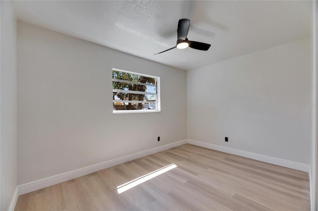 spare room with ceiling fan, light wood-style floors, a textured ceiling, and baseboards