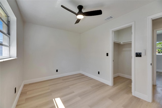 unfurnished bedroom with visible vents, light wood-style flooring, baseboards, and a spacious closet