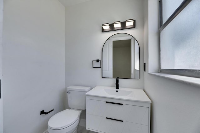 half bath with toilet, plenty of natural light, and vanity