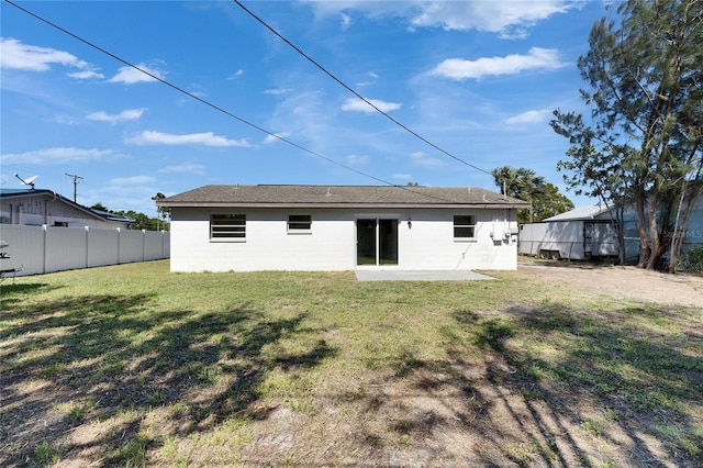 back of property featuring a yard, concrete block siding, a patio area, and fence