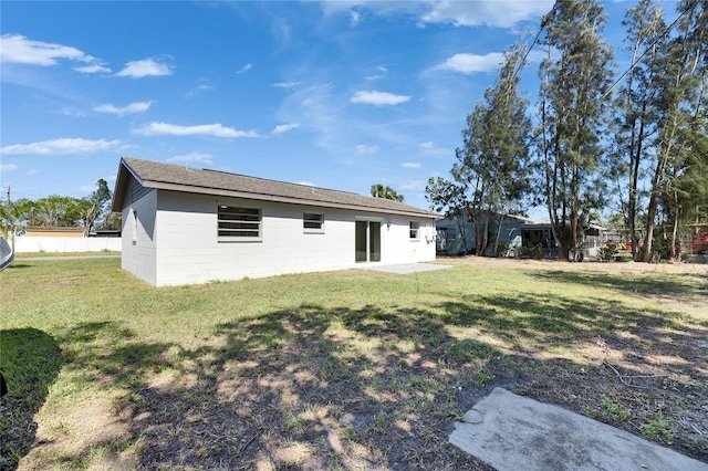 back of house with a patio area, fence, concrete block siding, and a lawn