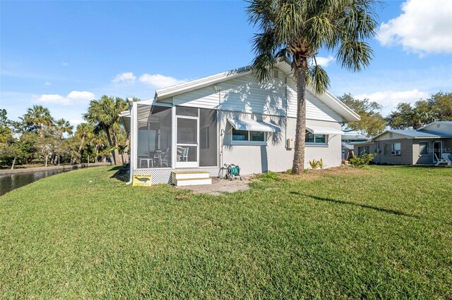 rear view of house with a yard and a sunroom