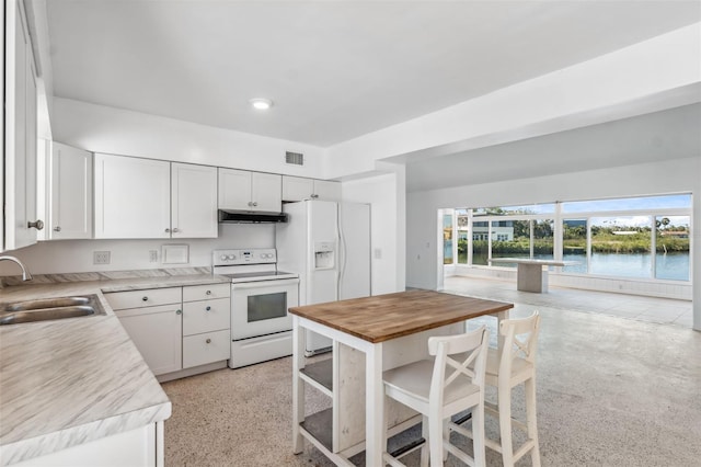 kitchen with a sink, under cabinet range hood, white appliances, white cabinets, and wooden counters