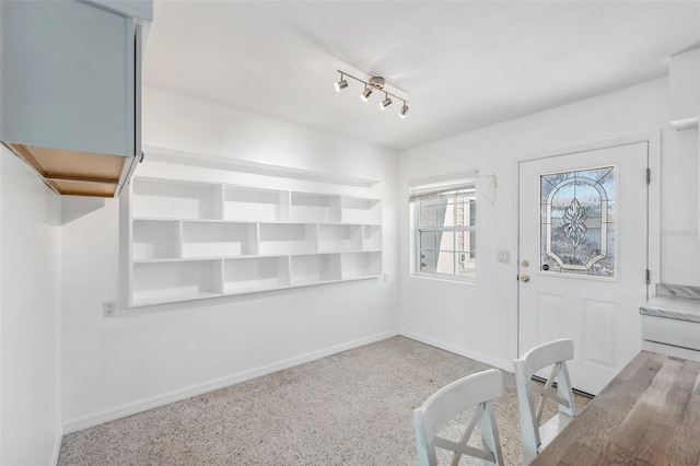 foyer featuring speckled floor and baseboards