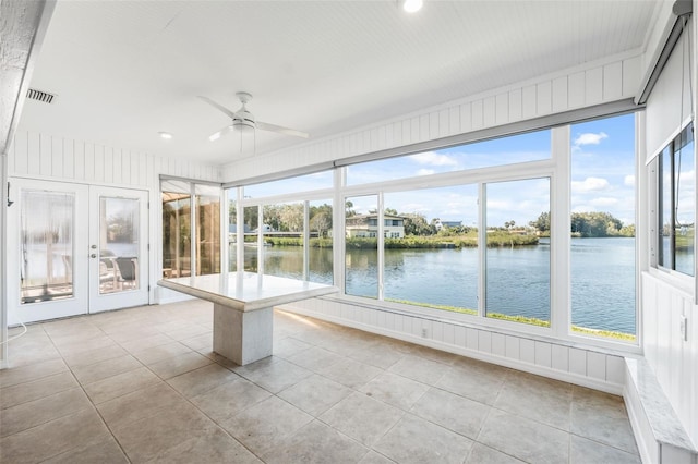 unfurnished sunroom featuring visible vents, a water view, a ceiling fan, and french doors