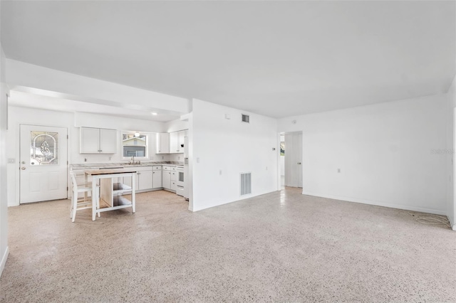 living room with light speckled floor, visible vents, and baseboards