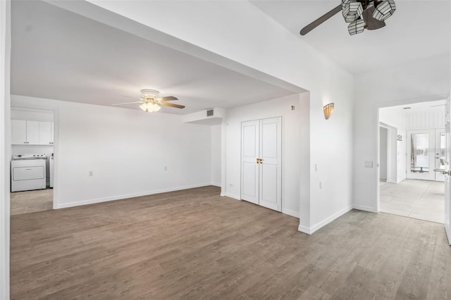 unfurnished living room with wood finished floors, a ceiling fan, baseboards, visible vents, and washer / clothes dryer