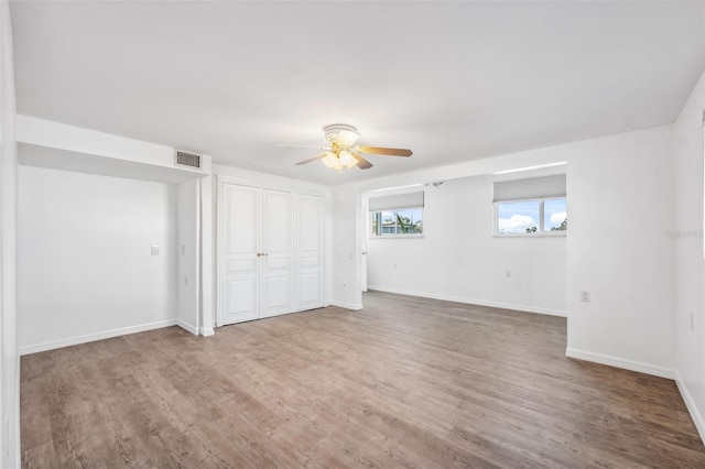 unfurnished bedroom with a ceiling fan, wood finished floors, visible vents, and baseboards