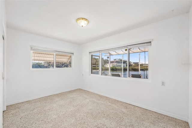 spare room with speckled floor and baseboards