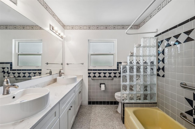 full bathroom featuring a sink, speckled floor, toilet, and tile walls