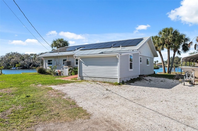 view of front of property with solar panels, driveway, metal roof, and a front lawn