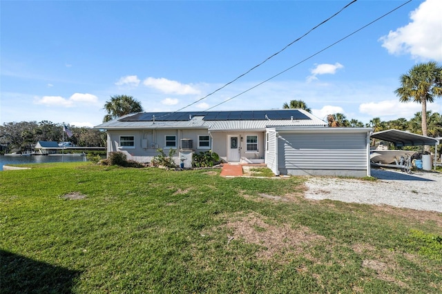 ranch-style home with solar panels, a carport, a yard, and driveway