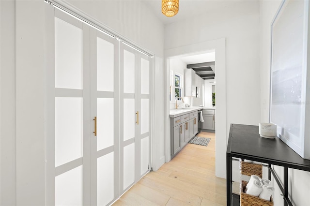 hallway featuring a sink and light wood-style floors