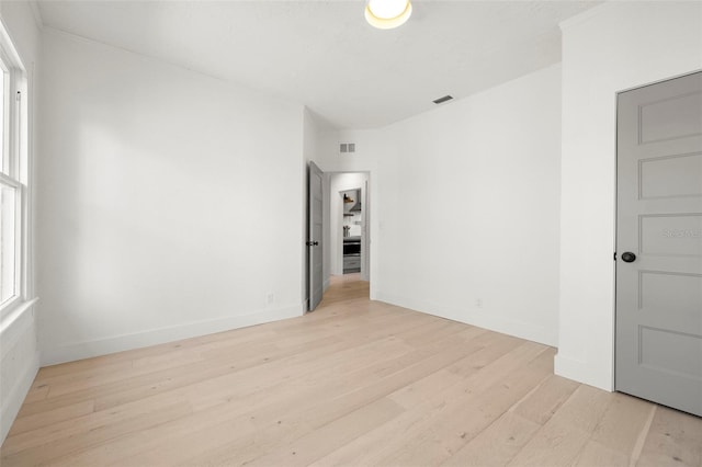 unfurnished room featuring baseboards, visible vents, and light wood-style floors