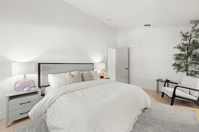 bedroom with visible vents, vaulted ceiling, and light wood-style flooring