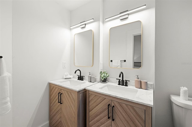 bathroom featuring two vanities, a sink, and toilet