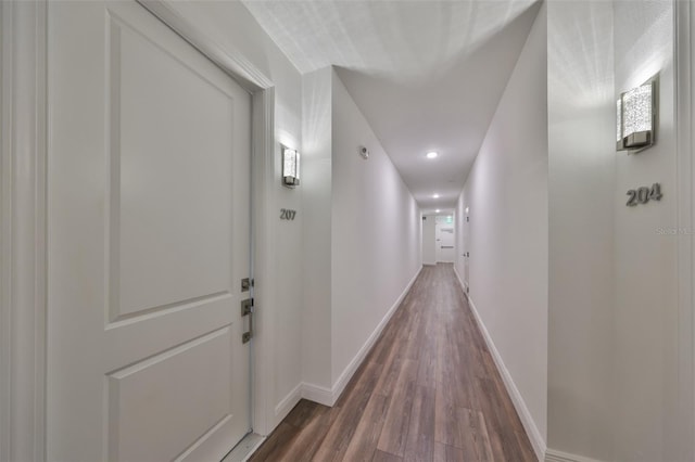 hallway featuring dark wood-style floors and baseboards