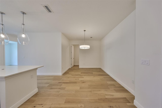 unfurnished dining area with light wood finished floors, baseboards, and visible vents