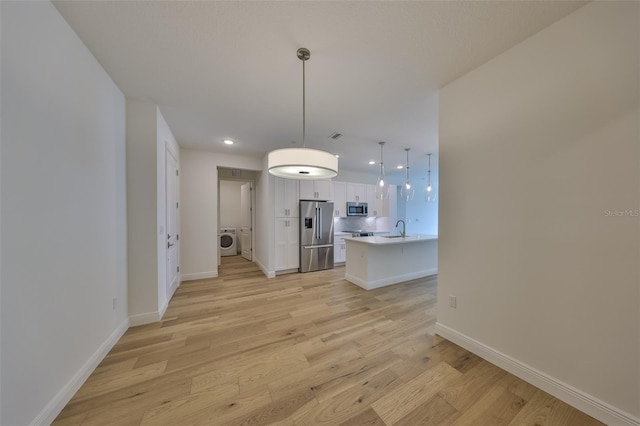 interior space with baseboards, washer / clothes dryer, light wood-style floors, a sink, and recessed lighting