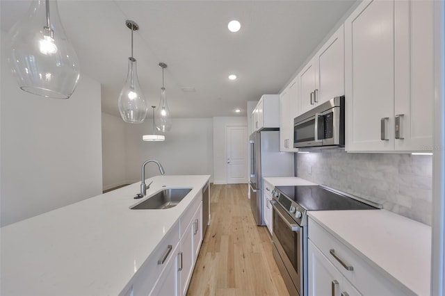 kitchen with light wood-style flooring, a sink, white cabinetry, appliances with stainless steel finishes, and tasteful backsplash