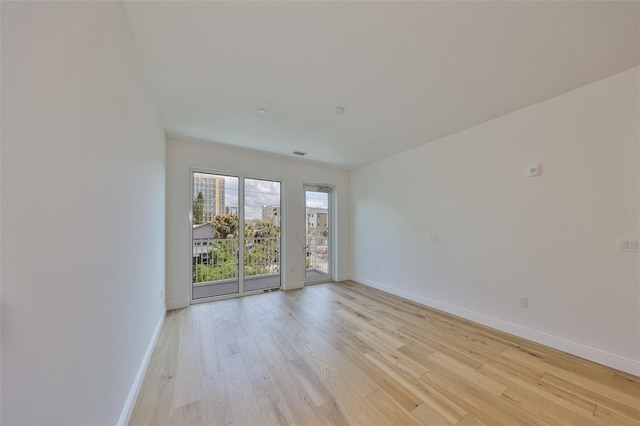 spare room featuring light wood-type flooring, visible vents, and baseboards