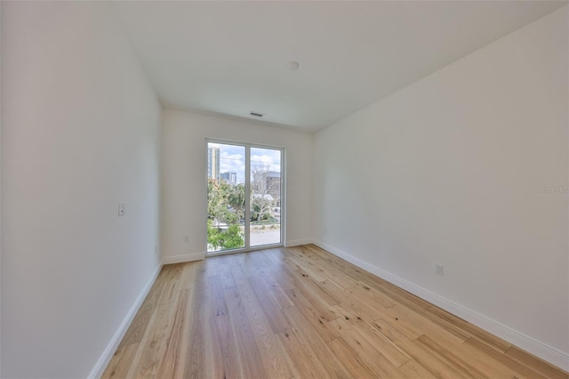 spare room featuring light wood-style floors, visible vents, and baseboards