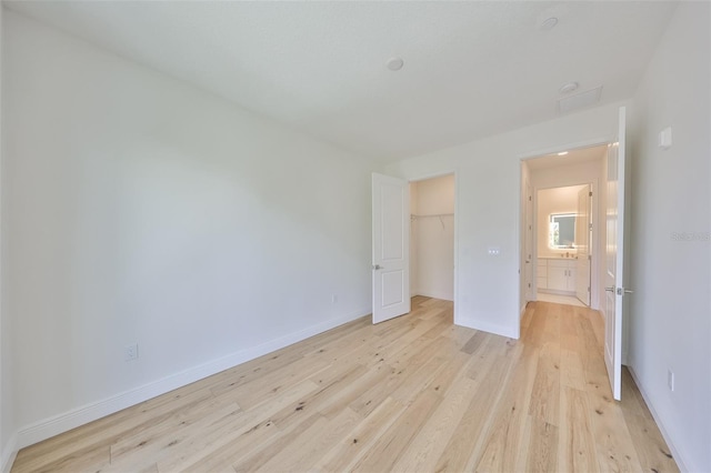 unfurnished bedroom with light wood-type flooring, baseboards, and a closet