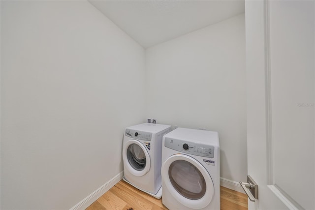 laundry room with laundry area, washer and clothes dryer, light wood-style flooring, and baseboards