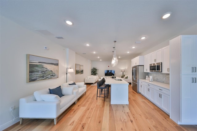 kitchen featuring open floor plan, appliances with stainless steel finishes, a breakfast bar, and white cabinets