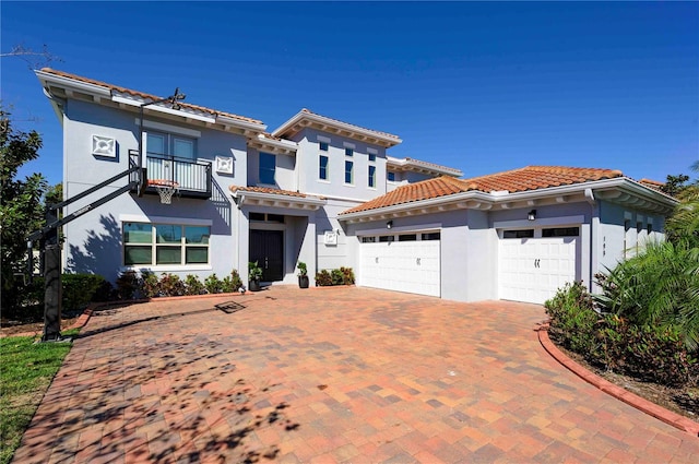 mediterranean / spanish-style house with an attached garage, a balcony, a tile roof, and stucco siding