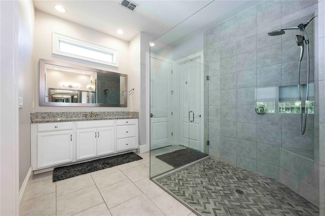 full bath with visible vents, a shower stall, vanity, baseboards, and tile patterned floors