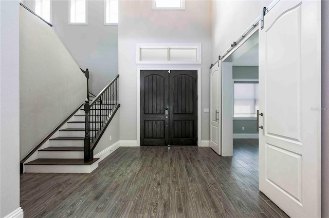 entryway with stairway, a barn door, baseboards, and dark wood-type flooring