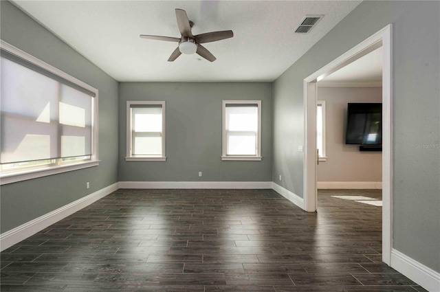 unfurnished room with a ceiling fan, dark wood-style flooring, visible vents, and baseboards