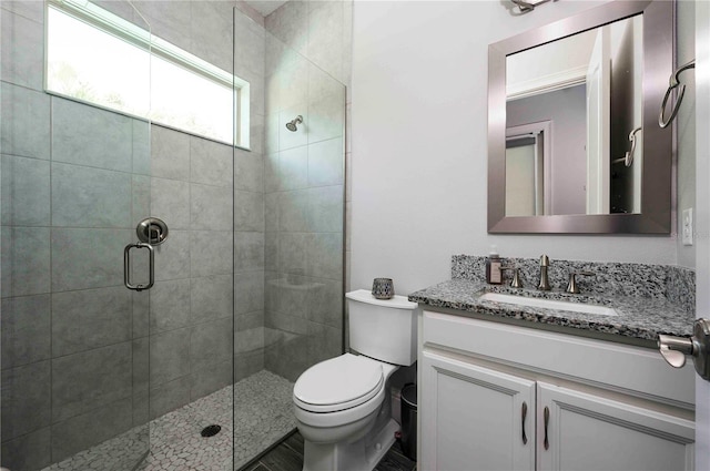 bathroom with a stall shower, vanity, and toilet