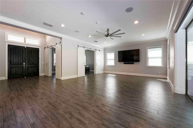 unfurnished living room featuring dark wood-style floors, a barn door, visible vents, and ceiling fan