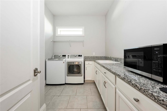 clothes washing area featuring light tile patterned flooring, a sink, and independent washer and dryer