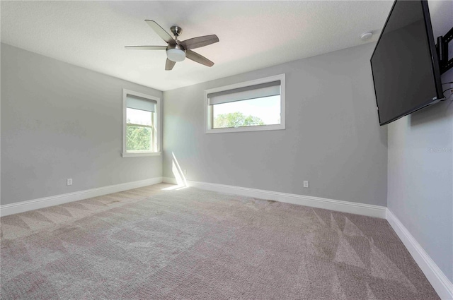 empty room with a ceiling fan, baseboards, and carpet flooring