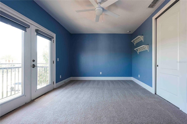 carpeted empty room featuring baseboards, visible vents, a ceiling fan, and french doors