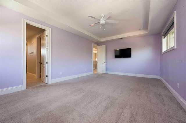 spare room featuring ceiling fan, baseboards, a raised ceiling, and carpet flooring